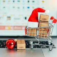 Christmas Online Shopping concept. Boxes with shopping cart on a laptop computer. Sale and discount during Christmas and New Year holiday, ecommerce, shipping delivery, logistics and Cyber Monday photo