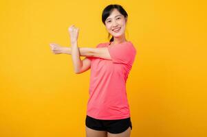 Portrait beautiful young asian sports fitness woman happy smile wearing pink sportswear posing exercise training workout isolated on yellow studio background. wellbeing and healthy lifestyle concept. photo