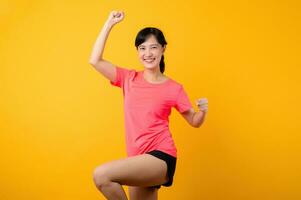 Portrait beautiful young asian sports fitness woman happy smile wearing pink sportswear posing exercise training workout isolated on yellow studio background. wellbeing and healthy lifestyle concept. photo