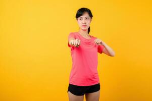 retrato hermosa joven asiático Deportes aptitud mujer contento sonrisa vistiendo rosado ropa de deporte posando ejercicio formación rutina de ejercicio aislado en amarillo estudio antecedentes. bienestar y sano estilo de vida concepto. foto