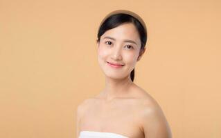 beauty asian young woman model with fresh glowing hydrated facial skin. girl person with natural makeup and healthy skin portrait isolated on beige studio background. spa treatment, skin care concept. photo