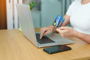 woman hand holding credit card and using laptop with mobile phone for online shopping while making order. Marketplace platform website, technology, ecommerce, digital banking and online payment photo