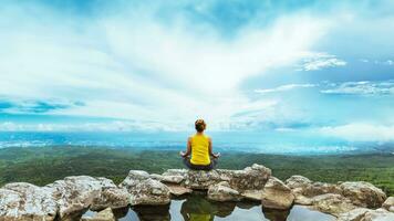 mujer asiática relajarse en las vacaciones. viajar relajarse. jugar si yoga. en el acantilado de roca de montaña. naturaleza de los bosques de montaña en tailandia foto