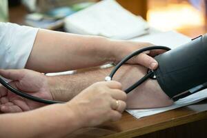 A doctor using a sphygmomanometer with a stethoscope revealed arterial hypertension in a patient in the hospital. photo
