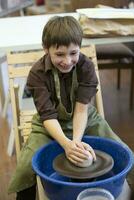 A little boy makes a clay product at a potter's wheel. photo