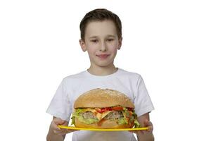 joven chico con grande hamburguesa aislado en blanco. un adolescente es participación un hamburguesa.creativa hamburguesa. foto