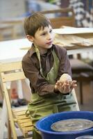 A little boy makes a clay product at a potter's wheel. photo