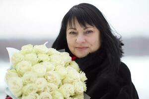 Beautiful elderly woman with a bouquet of roses photo