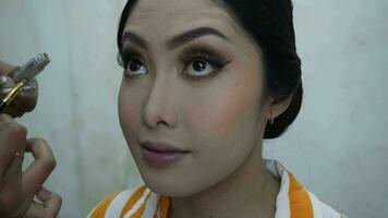linda jovem indonésio mulher obtendo profissional Maquiagem feito de uma Maquiagem artista às beleza salão video