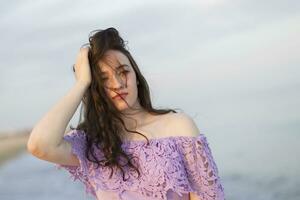 Young ordinary girl against the sky and the sea straightens her hair photo