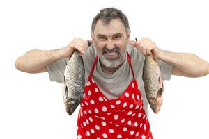 Mature fishmonger in red apron holding big freshwater fish and looking at camera on white background photo