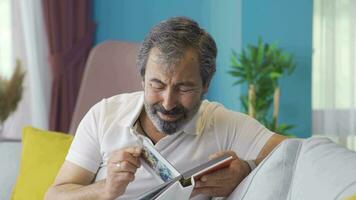 The man looking at his child's album cries with longing and his hand is shaking. video