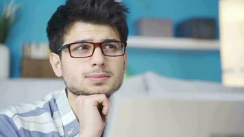 Thoughtful young man working on laptop finds a good idea. video