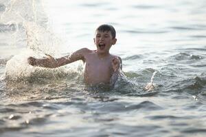 Happy teen boy plays with sea waves. The boy swims in the sea. photo