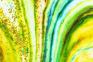 Multicolored colorful background of yellow and green paints in the form of stripes covered with gold sparkles. photo