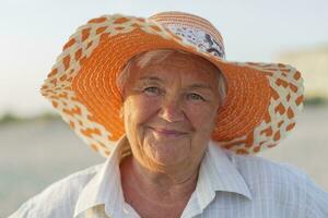 Beautiful elderly woman in a hat on the background of the sea. Face of an old woman with a smile. Grandma on vacation photo