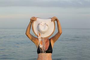 Female figure in sea water with a wide-brimmed hat photo