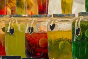 Glass jars with multi-colored lemonade. Bright summer drinks with fruits and herbs photo