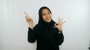 young asian woman using finger pointing in different directions with blank copy space standing over isolated white background. Pointing finger. Giving directions photo