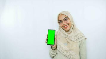 young asian woman showing copy space on her phone screen. Isolated over white background photo