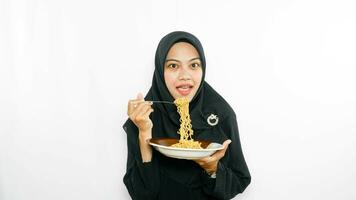 Young asian woman isolated on white background holding a plate of noodles with fork and eating it photo