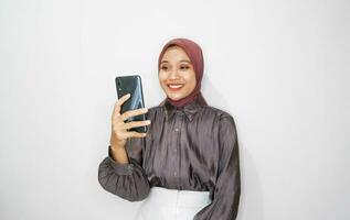 Portrait of happy young muslim woman talking on mobile phone against white background photo