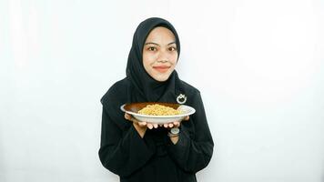 Young asian woman isolated on white background holding a plate of noodles with fork and eating it photo