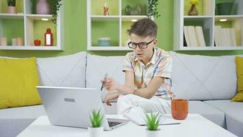 pequeño chico soñando de convirtiéndose un empresario. él trabajos a hogar en un ordenador portátil. video