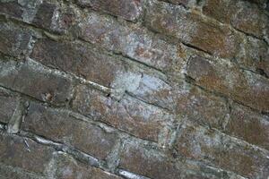 Weathered brick layer wall background, grungy brick texture surface, aged wall texture photo