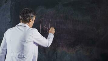 Male doctor writes Polyclinic on the blackboard. video