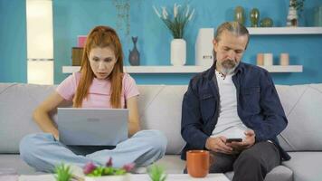 Daughter shows her father the news on the laptop. They comment together. video