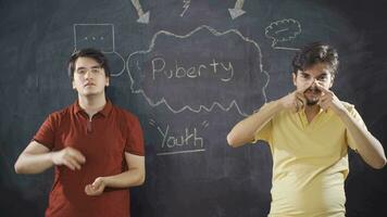 Young man writing Puberty on blackboard. video