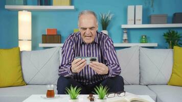 Cheerful old man is excitedly watching something on the phone. video