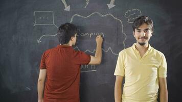 Young man writing Camping on blackboard. video