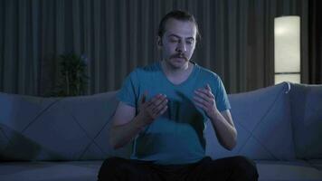 Young man praying at home at night. video