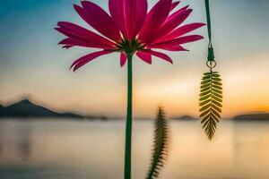 a pink flower is hanging from a hook in front of a lake. AI-Generated photo