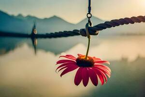 a flower hanging from a rope in front of a lake. AI-Generated photo