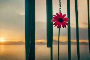 a red flower is hanging from a chain by the water. AI-Generated photo