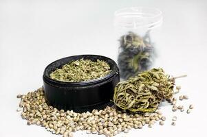 hierba amoladora lleno de aplastada brotes y seco flores de médico marijuana rodeado por semillas cerca arriba en blanco antecedentes foto