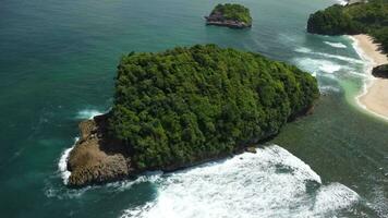 Orbital Aerial view of a small island covered with tropical trees at Tanjung Penyu Mas Beach video