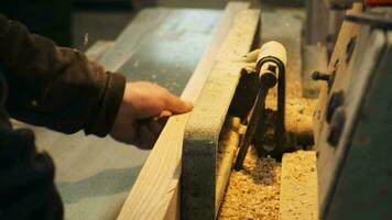 Carpenter works on the jointer-planer or surface planer with wooden plank. Woodworking machine producing elements for furniture video