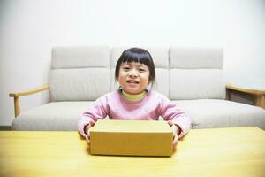 auténtico asiático hija felicidad sonriente retrato con un paquete o empaquetar en de madera mesa foto