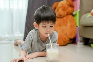 Asian boy is drinking a glass of milk photo