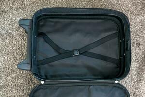 un vacío negro maleta laico en el piso, esperando a ser cargado. foto