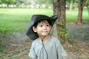 sonriente asiático chico vistiendo un sombrero en un selva exploración traje foto