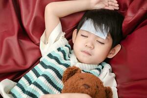 Asian boy She was sick and had a fever reducing patch on her forehead. She was lying on the bed. photo