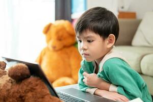 Asian boy studying online and doing activities on laptop photo