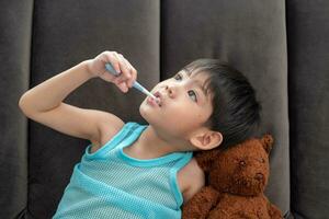 asiático chico cepillado su dientes en el vivo habitación foto