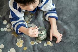 asiático chico felizmente contando monedas a salvar dinero foto