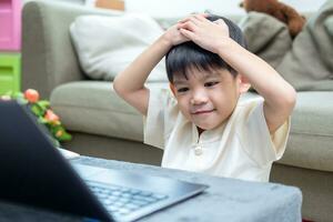 Asian boy studying online on laptop photo